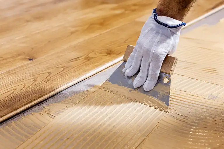 Closeup of hand spreading flooring adhesive