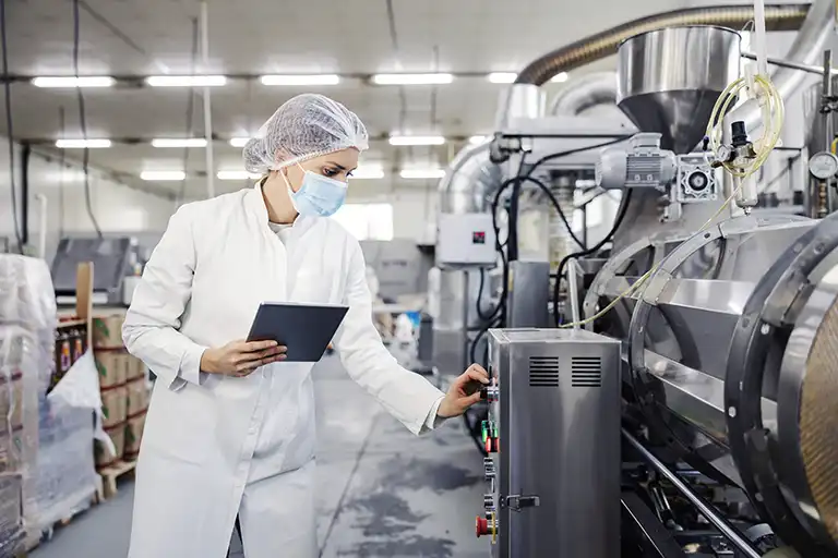 Person in white coat and mask working in food manufacturing facility